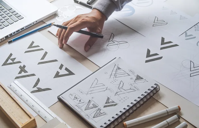 Caderno com esbocos de identidade visual e lapis sobre a mesa