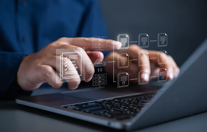 Maos digitando em notebook com icones de documentos digitais